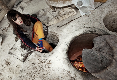  Arevik , a daughter of the armenian traditional bread-backer's family, warmes her legs up in the floor's holes warmed by the  earthoven called ‟tandir‟.  Armenia. March. 2010.